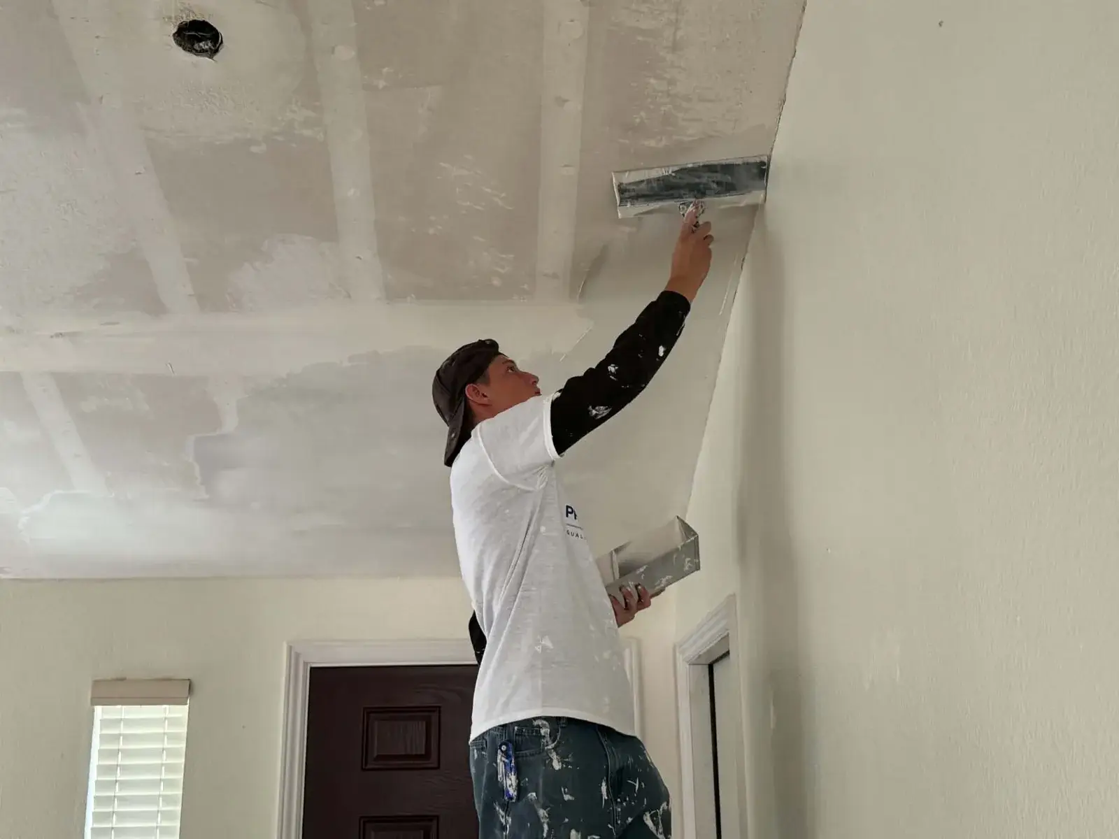 Worker smoothing ceiling joint compound with a wide finishing knife